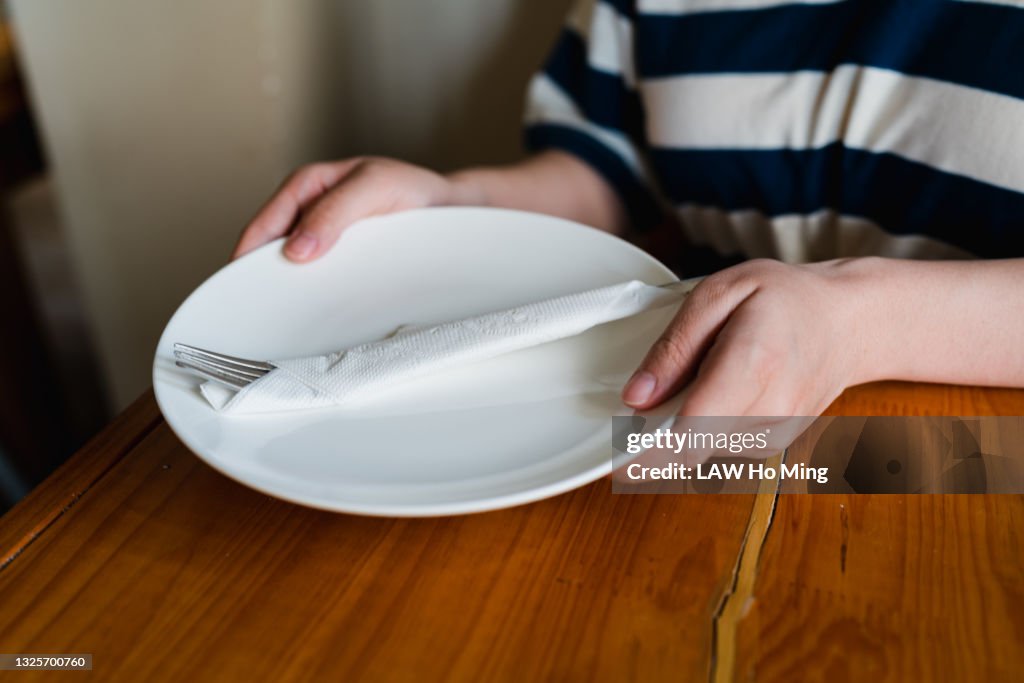 An Asian woman is distributing empty plates on a wooden table