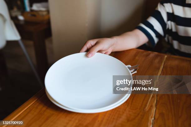 an asian woman is distributing empty plates on a wooden table - empty plate stock pictures, royalty-free photos & images