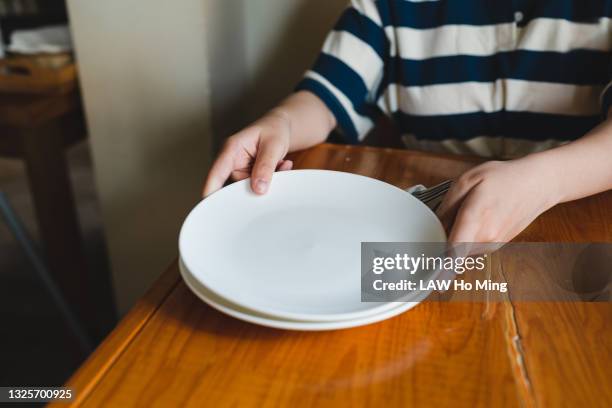 an asian woman is distributing empty plates on a wooden table - woman empty plate stock pictures, royalty-free photos & images