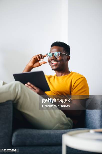 work from home:smiling young african american using tablet - gul bildbanksfoton och bilder