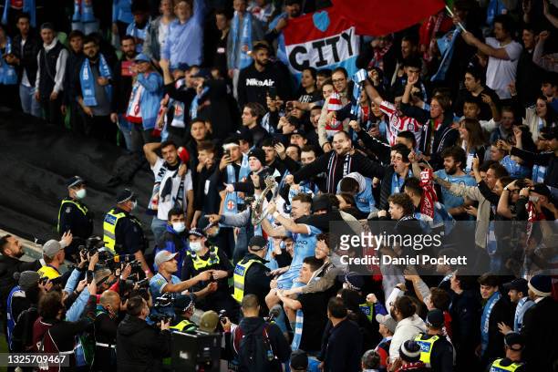 Scott Galloway of Melbourne City holds the trophy and celebrates with fans after winning the A-League Grand Final match between Melbourne City and...