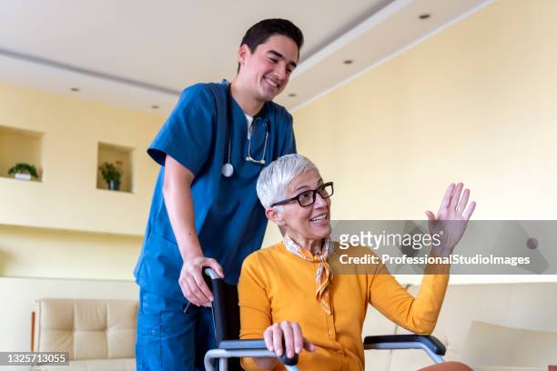 青い制服を着た医師が車椅子に乗った先輩女性を訪ねている。 - stretcher ストックフォトと画像