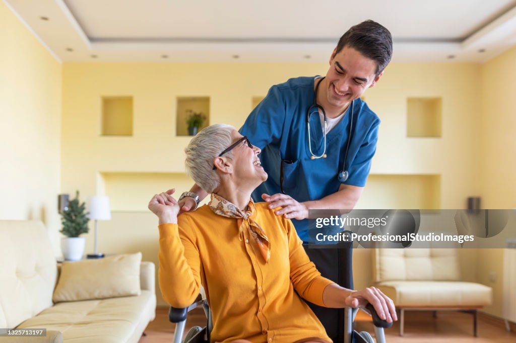 Gesundheitshelfer in Hausbesuch bei einer älteren Frau mit körperlichen Behinderungen.