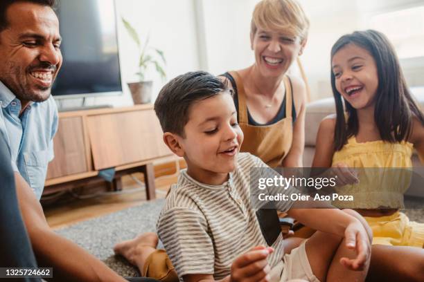 happy hispanic and caucasian family with two sons playing and writing on a board in living room of their new home - spieleabend stock-fotos und bilder