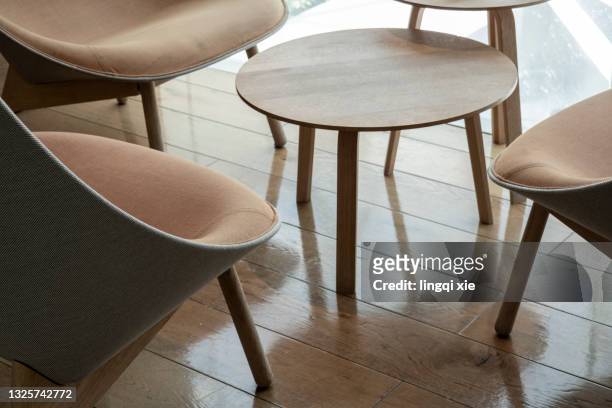 wooden chairs around a round coffee table - clean wood table stock-fotos und bilder