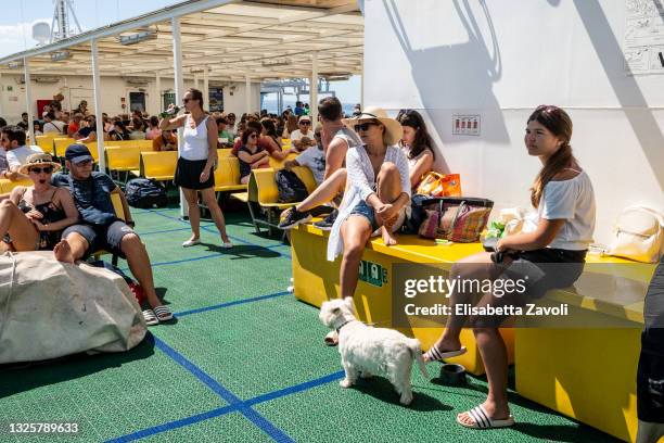 Tourists sunbath on the outer deck of the domestic ferry connecting Split to Brac island on June 27, 2021 in Croatia. In outdoor spaces face masks...