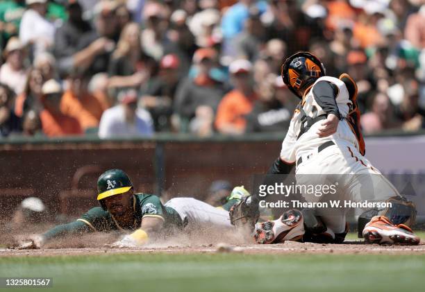 Tony Kemp of the Oakland Athletics slides past the tag of Buster Posey of the San Francisco Giants to score in the top of the sixth inning at Oracle...