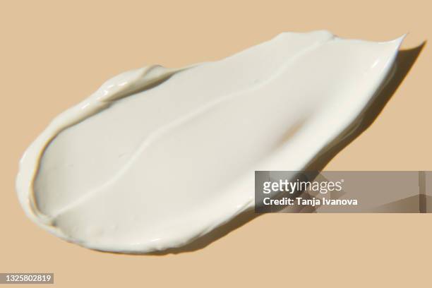 liquid textured smear of white cream on beige background. flat lay, top view, copy space. cosmetic banner. - creme stock-fotos und bilder