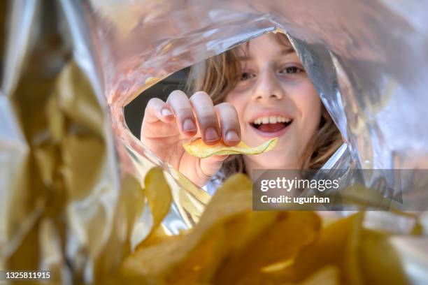 un niño comiendo patatas fritas de un paquete. - bag of chips fotografías e imágenes de stock