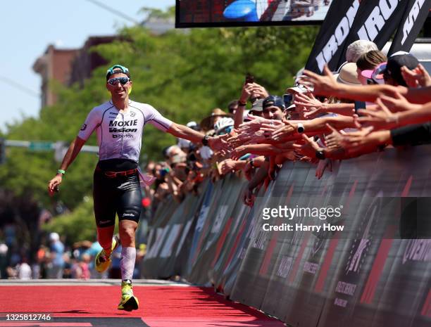 Pedro Gomes of Spain celebrates with fans as he heads to the finish line for third place during IRONMAN Coeur d'Alene on June 27, 2021 in Coeur...