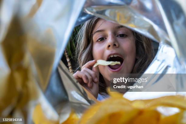 un niño comiendo patatas fritas de un paquete. - bag of chips fotografías e imágenes de stock