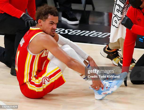 Trae Young of the Atlanta Hawks holds his ankle after an injury during the second half in game three of the Eastern Conference Finals against the...