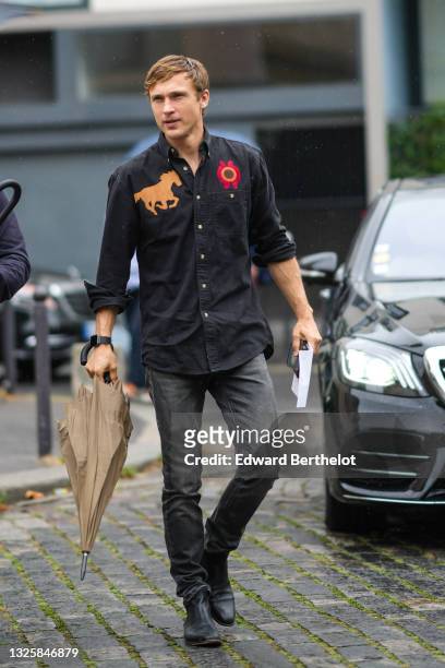 Actor William Moseley wears a black shirt with brown suede horse embroidered and red / brown embroidered circle, a black watch from Apple, gray faded...
