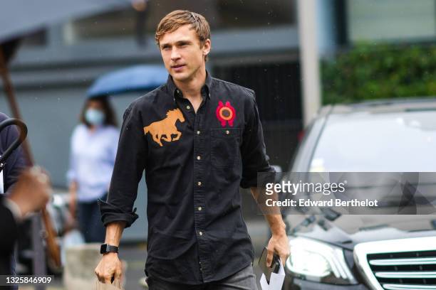 Actor William Moseley wears a black shirt with brown suede horse embroidered and red / brown embroidered circle, a black watch from Apple, gray faded...