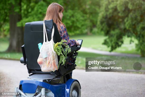 woman in wheelchair with fresh food shopping in reusable bag. - motorized wheelchair stock pictures, royalty-free photos & images