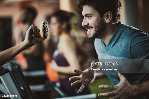 athletic man running on treadmill while craving for sweet donut. - man running food stock pictures, royalty-free photos & images