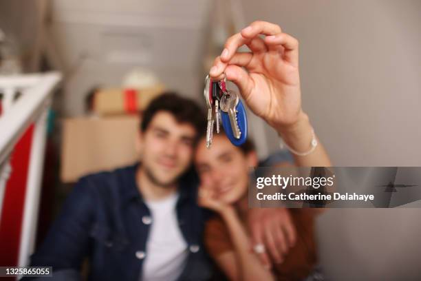 a happy young couple moving into a new apartment - llave de la casa fotografías e imágenes de stock