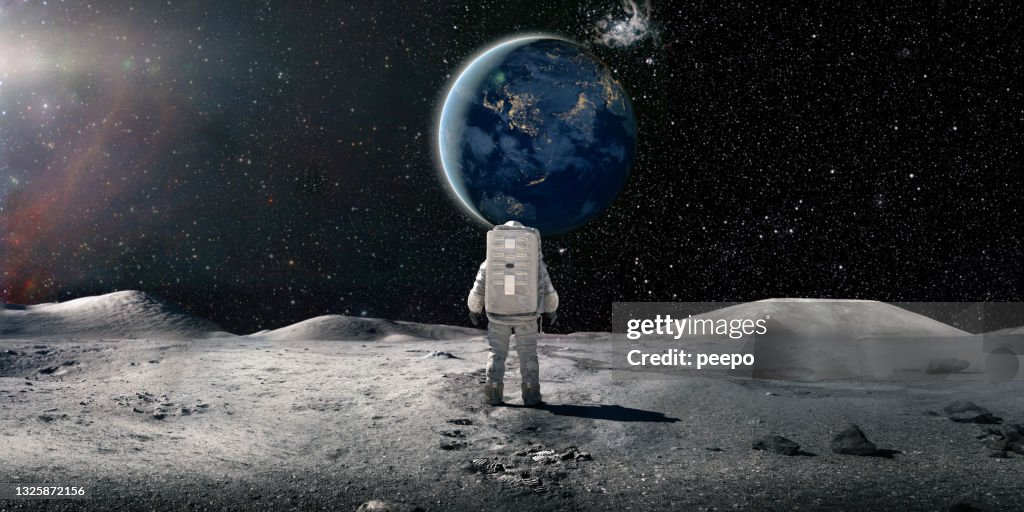 Astronauta solitário em traje espacial em pé na Lua olhando para a Terra Distante
