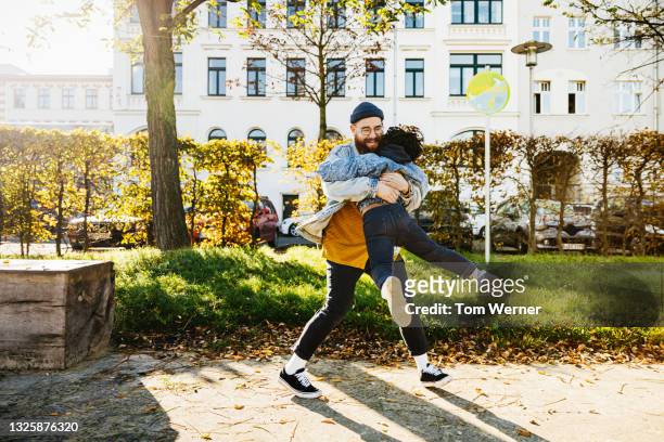 dad swinging young son around while playing in park - embracing change stock pictures, royalty-free photos & images