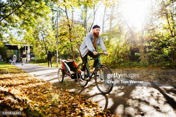 dad riding bike with trailer for toddler attached - fahrrad natur stock-fotos und bilder