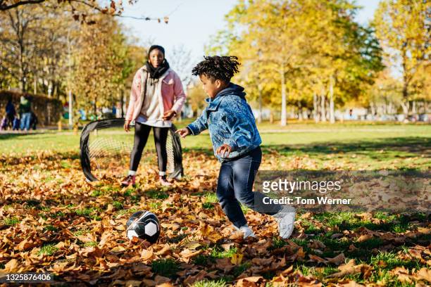 young boy shooting while playing soccer with family - blue hose soccer stock-fotos und bilder