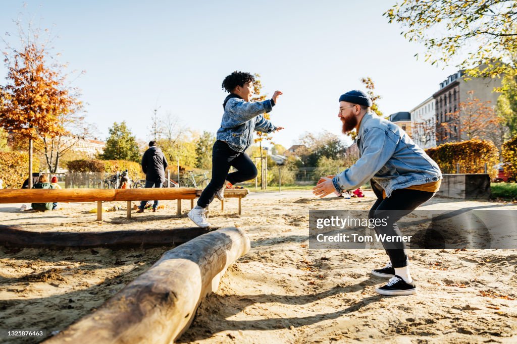 Young Boy Leaping Into Father Arms In Playground