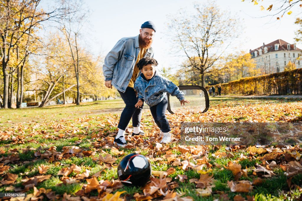 Dad Playing Soccer With Son In Park