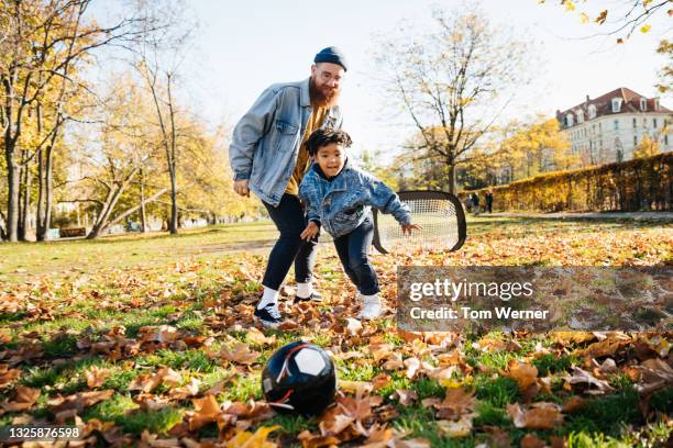 dad playing soccer with son in park - sports balls foto e immagini stock