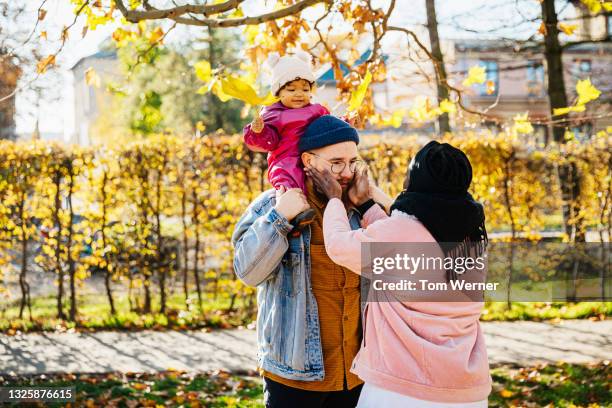 toddler sitting on dad's shoulders at the park - adult baby women stockfoto's en -beelden