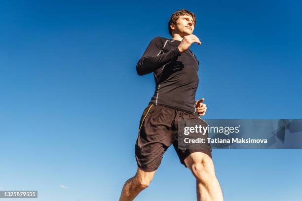 man running on sky background. - man blue background - fotografias e filmes do acervo