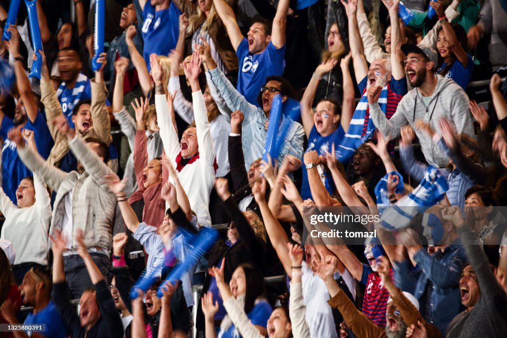 Spectators cheering on a stadium for the blue team