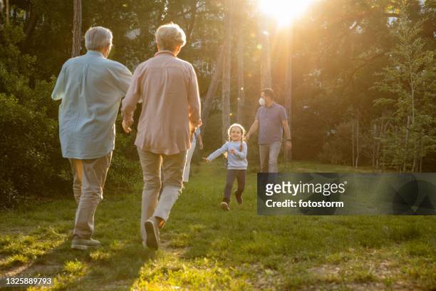 little girl running to her grandparents embrace - park family sunset stock pictures, royalty-free photos & images