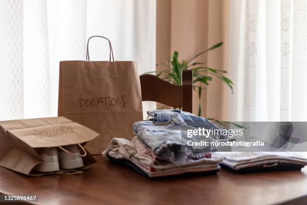 folded clothes on the table ready to donate - belongings stock-fotos und bilder