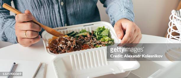 man having lunch from recycled bowl and using laptop. concept of food delivery, quarantine, take out food. banner for web page - buckwheat isolated stock pictures, royalty-free photos & images