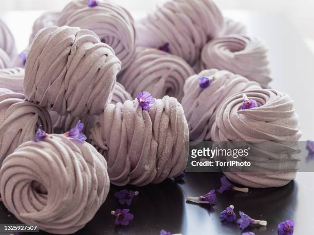 heap of pink color marshmallows on black table with purple flowers - agargel stock-fotos und bilder