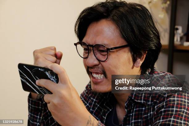 man playing games on a smartphone - horizontaal stockfoto's en -beelden