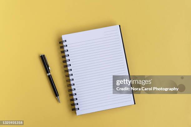 notepad and pen on yellow background - spiral notebook table stock pictures, royalty-free photos & images