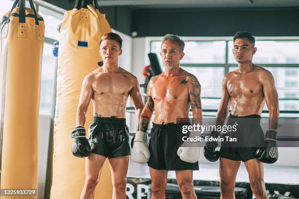 porträt asiatische chinesische muay thai senior mann lehrer mit seinem studenten vor boxring - bodybuilding furious stock-fotos und bilder