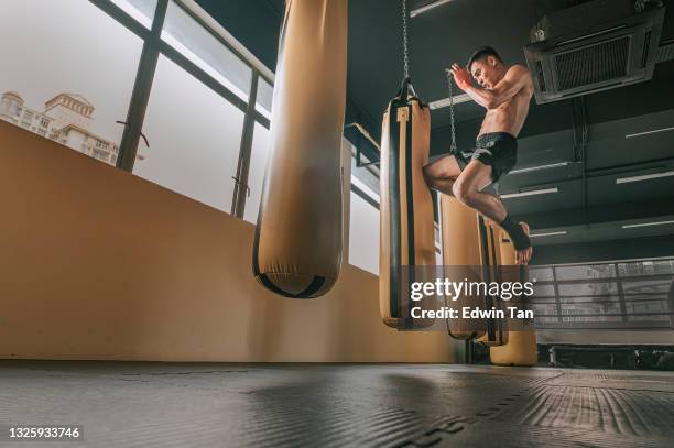 asian malay muay thai boxing boxer flying kick punching bags in gym health club - 技擊運動 個照片及圖片檔