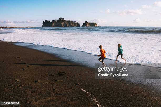 i bambini giocano nel surf nell'oceano pacifico - olympic peninsula foto e immagini stock