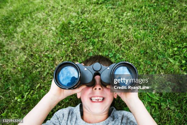 boy looking at clouds with binoculars - verrekijker stockfoto's en -beelden