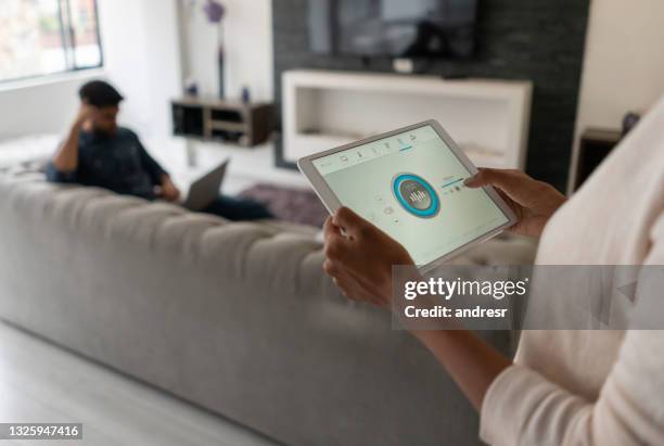 mujer que vive en un hogar inteligente y controla la música desde su tableta - hi fi fotografías e imágenes de stock