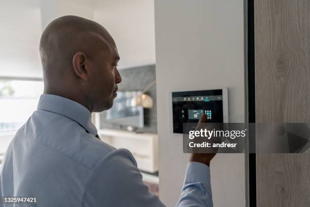 agente inmobiliario cerrando la puerta de una casa mediante un sistema domótico - alarma de seguridad fotografías e imágenes de stock