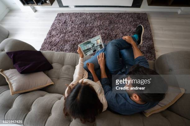 pareja en una videollamada con su agente de bienes raíces y haciendo un recorrido virtual de una casa en venta - red tour fotografías e imágenes de stock