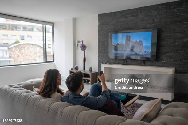 couple relaxing at home watching a movie on the tv - young couple watching tv stock pictures, royalty-free photos & images