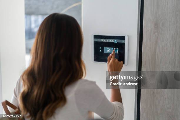 mujer cerrando la puerta de su casa usando un sistema domótico - alarma de seguridad fotografías e imágenes de stock