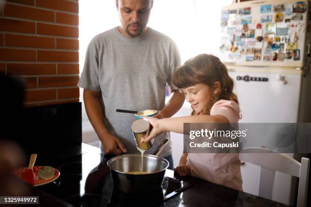 bambina che versa gli ingredienti nella padella per fare ganache - condensed milk foto e immagini stock
