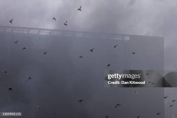 Pigeons fly through the smoke as firefighters tackle a blaze nearby the Elephant & Castle Rail Station on June 28, 2021 in London, England. London...