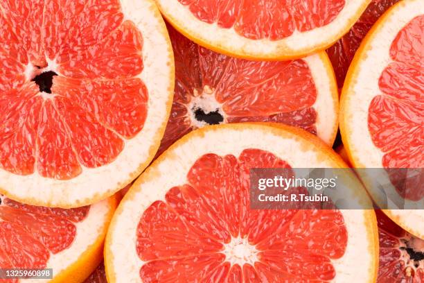 abstract red background with citrus-fruit of grapefruit slices. close-up - pompelmo foto e immagini stock