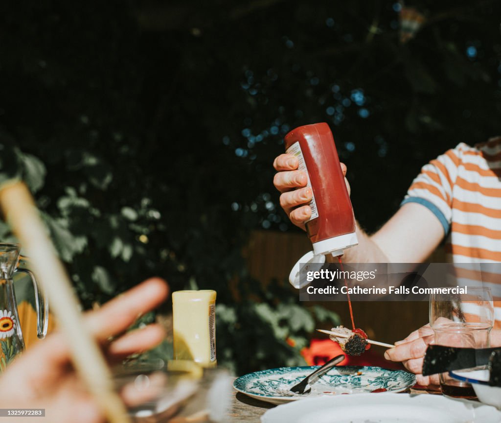 Man squeezes tomato sauce onto a kebab during an al fresco dining experience